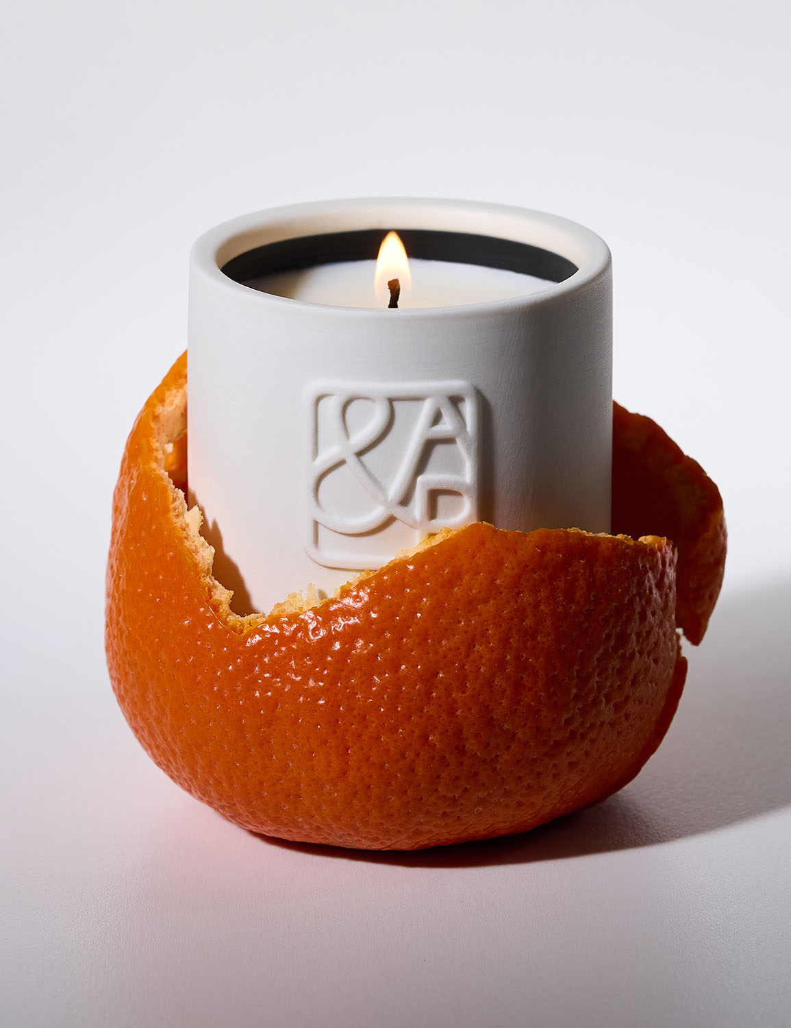 AUGUST&PIERS luxury candle in white ceramic vessel wrapped in fresh orange peel – citrus inspired home fragrance.