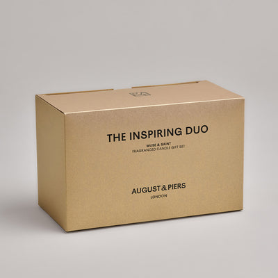 The Inspiring Duo Gift Set by AUGUST&PIERS London. This set features the Muse and Saint candles in limited-edition light gold packaging.