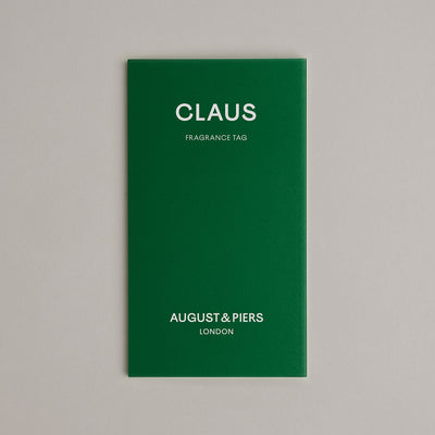 Green fragrance tag with 'Claus' and 'August & Piers London' text on a gray background
