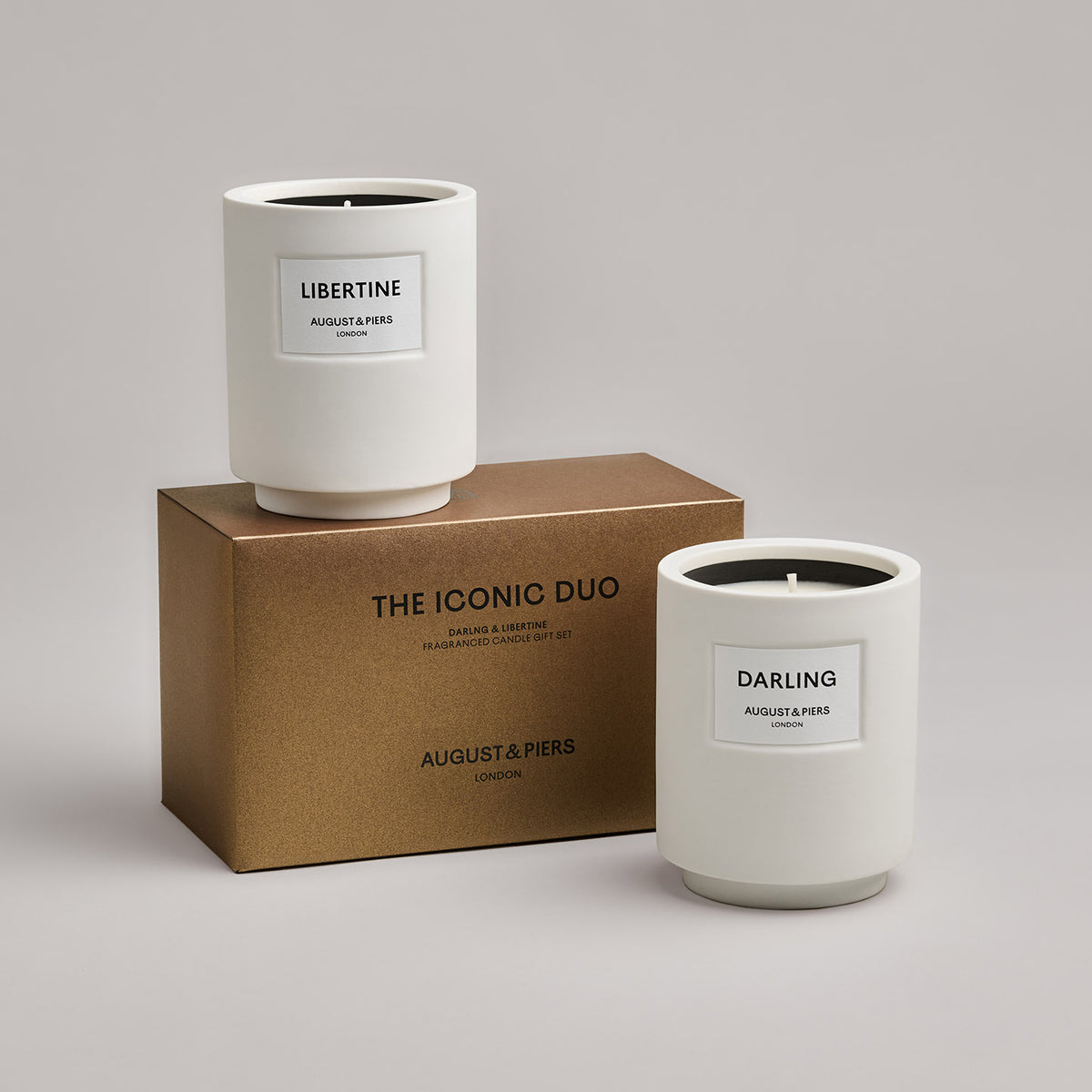 The Iconic Duo Gift Set by AUGUST&PIERS London. Two classic ceramic candles are packaged in a limited-edition dark gold box. This set features the Darling and Libertine candles.