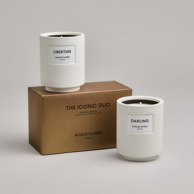 The Iconic Duo Gift Set by AUGUST&PIERS London. Two classic ceramic candles are packaged in a limited-edition dark gold box. This set features the Darling and Libertine candles.