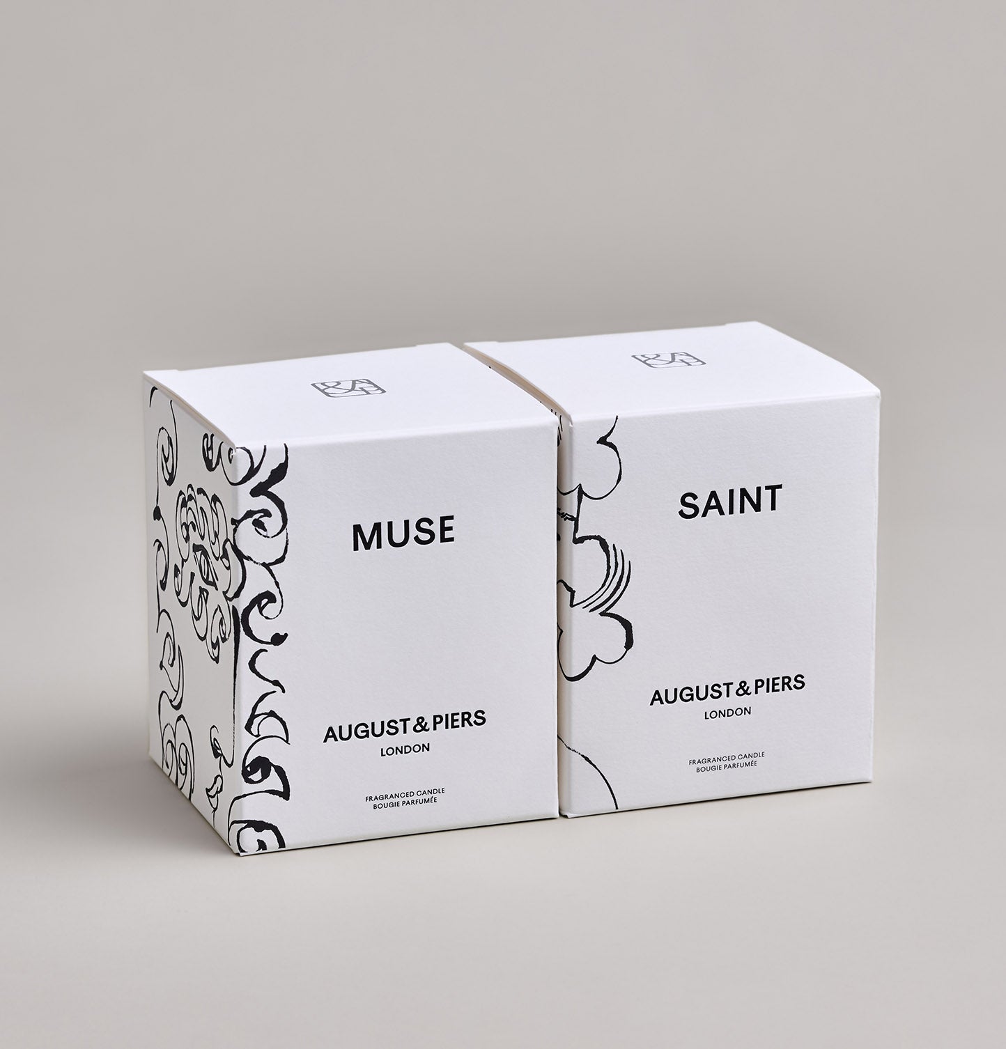 The Inspiring Duo Gift Set by AUGUST&PIERS London. Two classic ceramic candles are packaged in a limited-edition dark gold box. This set features the Muse and Saint candles.
